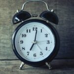 Classic black analog alarm clock on rustic wooden background, perfect for time and nostalgia themes.